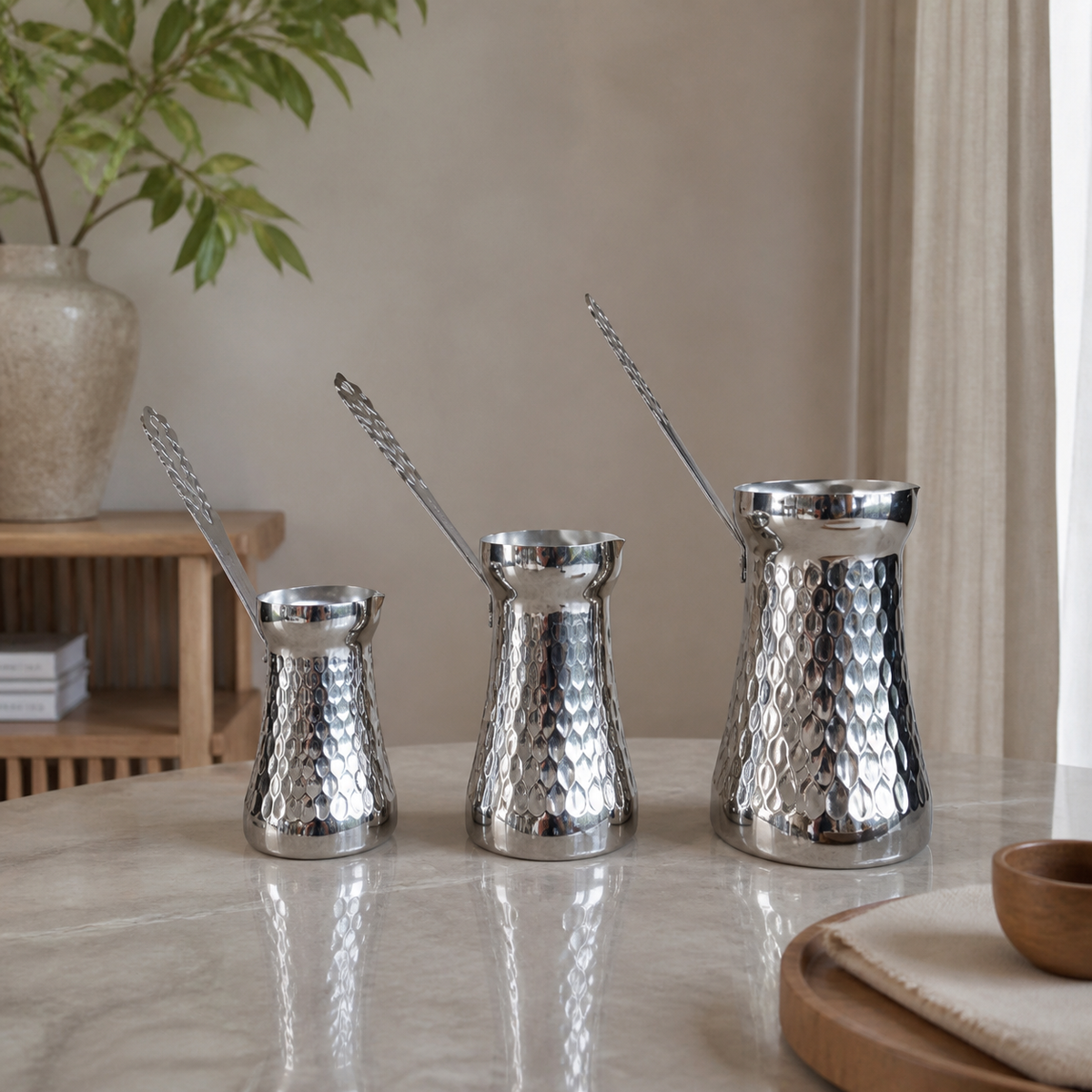 Silver three-piece coffee pot set with dimpled bodies, styled on a marble table