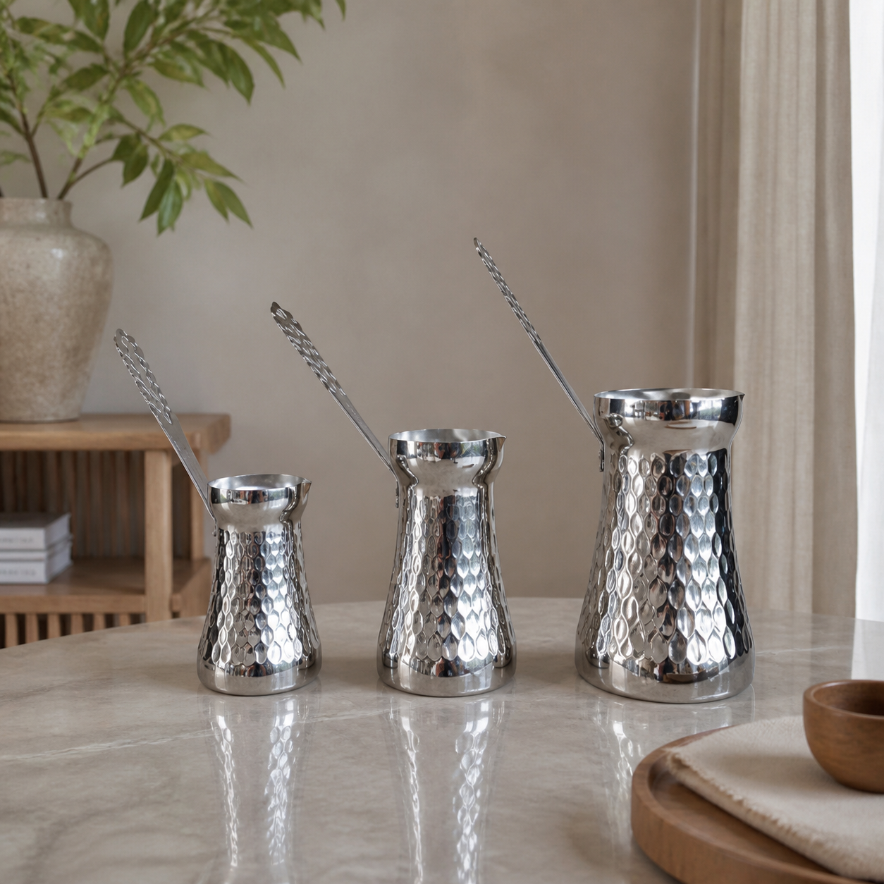 Silver three-piece coffee pot set with dimpled bodies, styled on a marble table