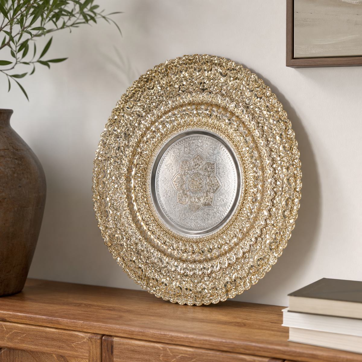 Round gold filigree tray with engraved silver centre, on a wooden sideboard
