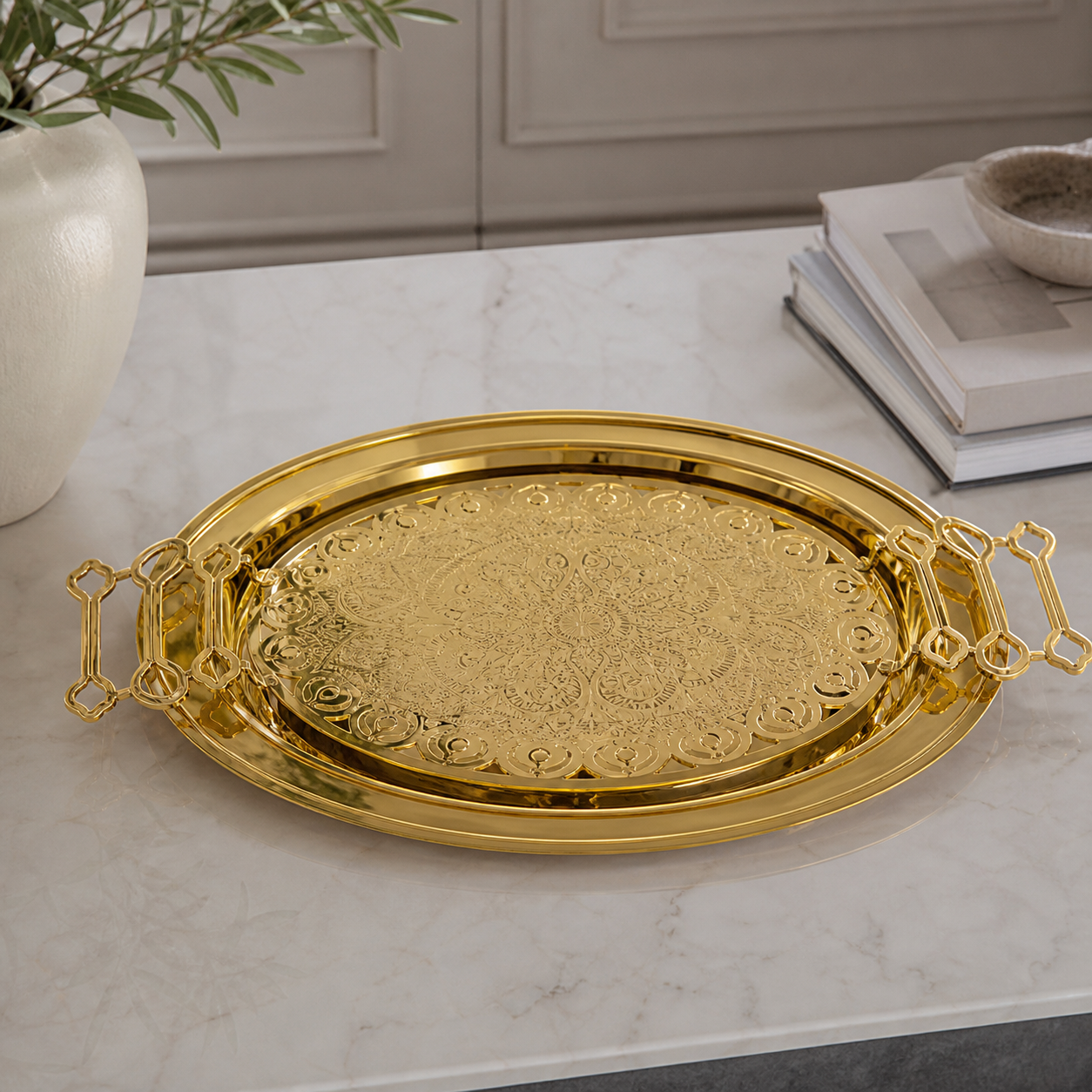 Gold-tone serving tray with ornate openwork handles and an engraved centre medallion, on a marble table
