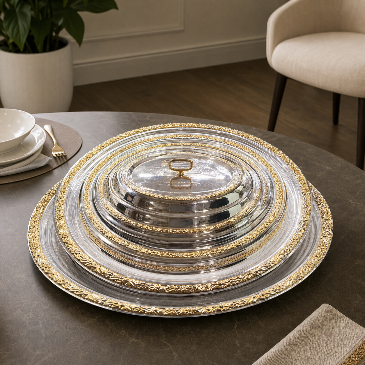 Silver and gold filigree serving trays with a domed cover on a dark dining table