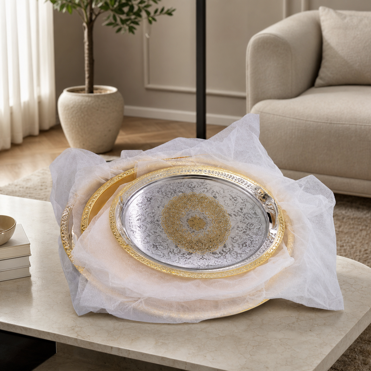 Wrapped three-tray stack on a marble table; only the top tray engraved silver face is visible