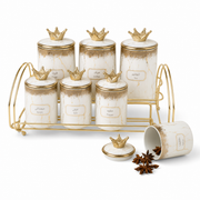Seven white and gold marbled ceramic canisters with crown lids on a gold-tone stand