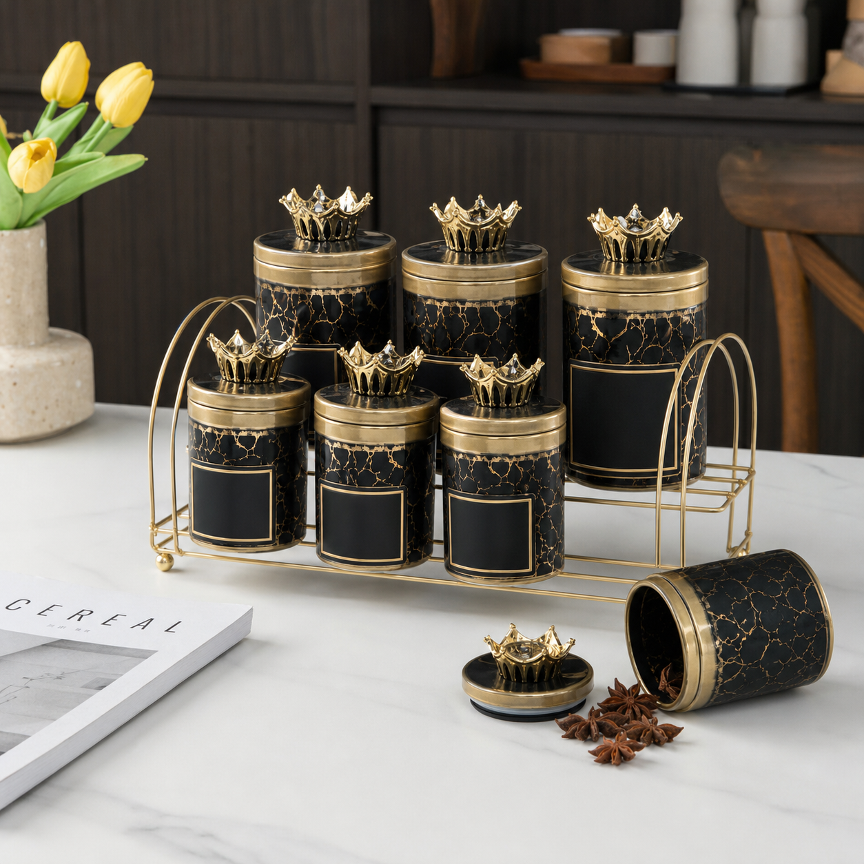 Black jars with gold crackle pattern and stone-set crown lids on a gold-tone stand, marble worktop