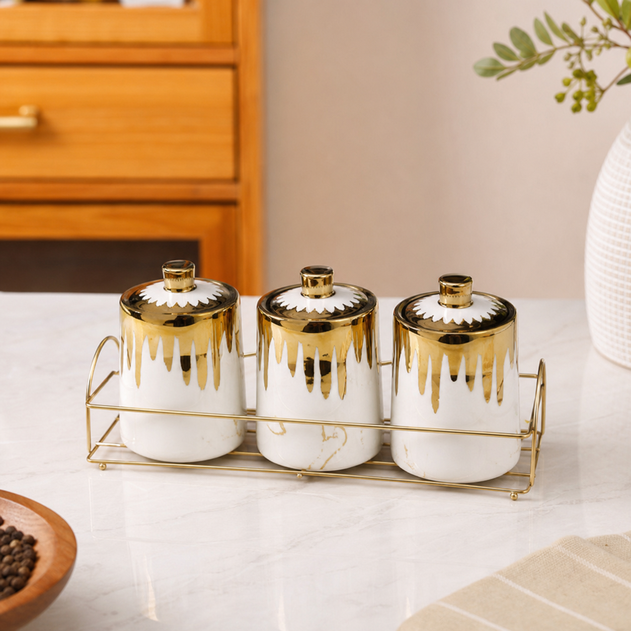 White and gold drip-glaze ceramic canister set on its gold-tone rack on a kitchen counter