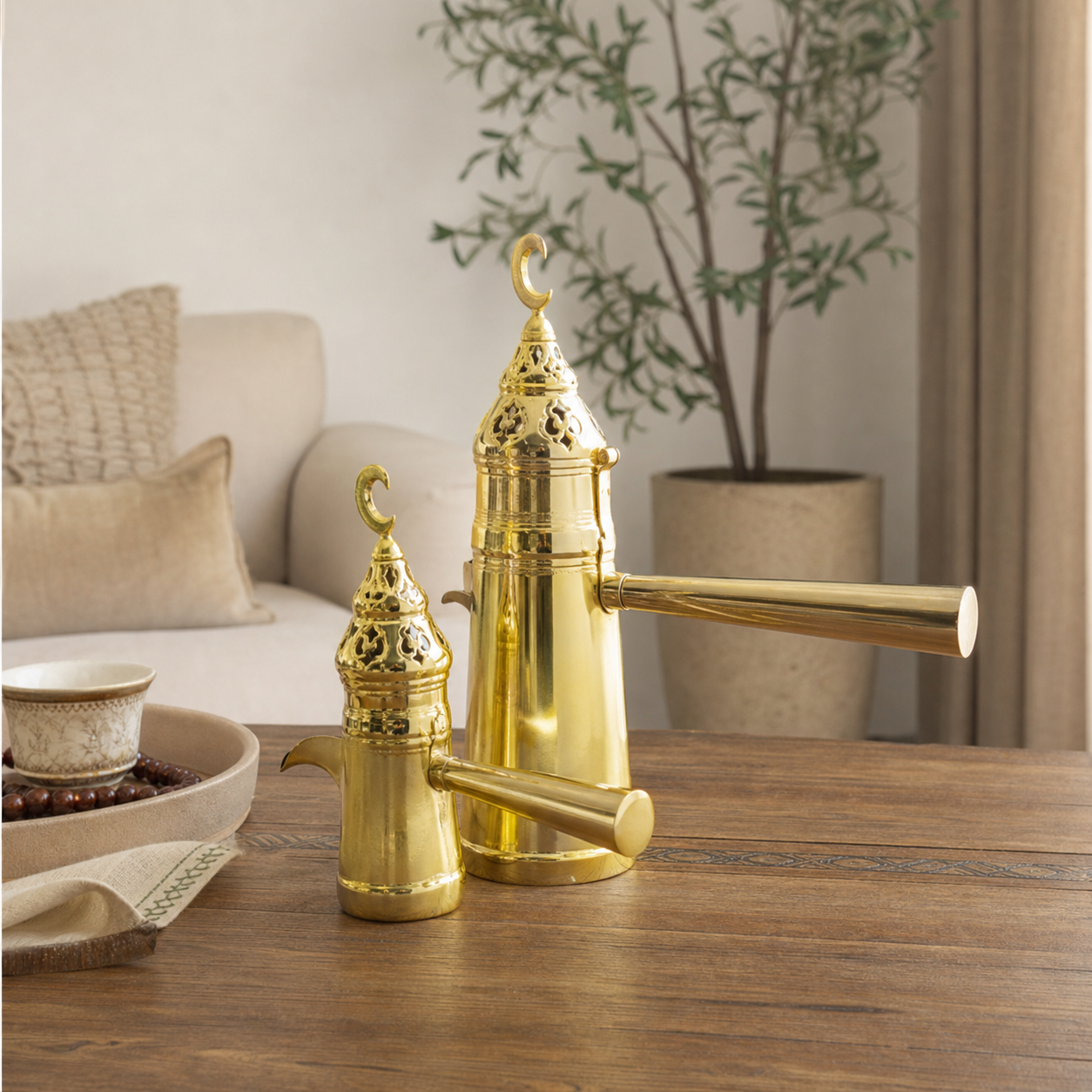 Two gold-tone coffee pots with pierced lids and plain crescent finials on a wooden table