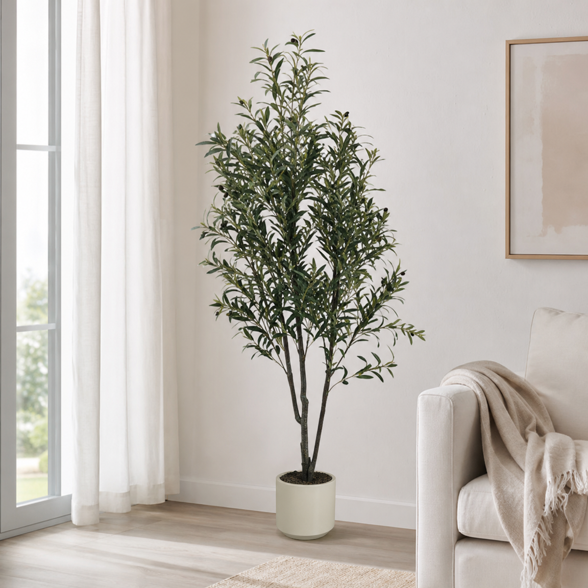 Artificial olive tree in a beige planter, standing on a living-room floor beside a sofa
