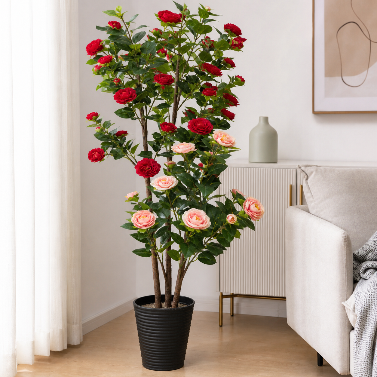 Artificial rose tree with red and pink blooms in a ribbed black pot, in a living room