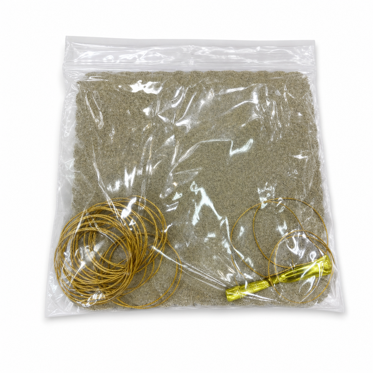 Clear bag with two coils of gold-tone cord and a gold-tone tube over beige granular fill