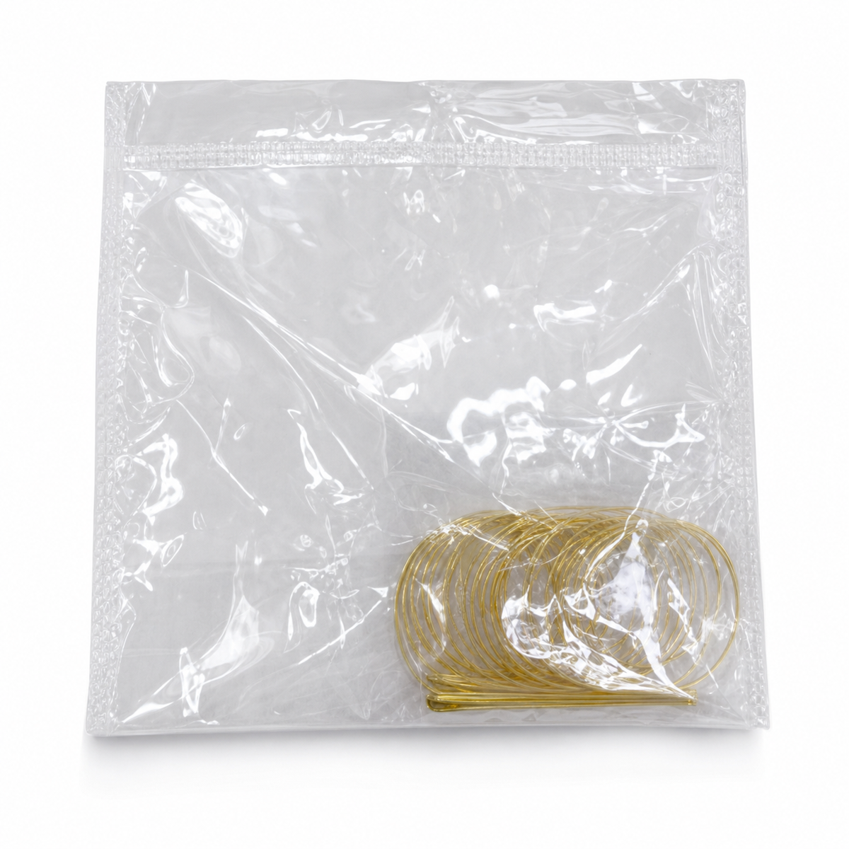 Coil of slim gold-tone hoops sealed in a clear zip-top bag on a white background