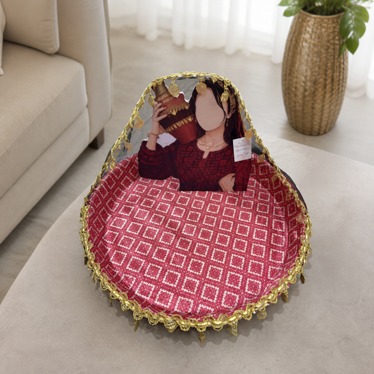 Red and gold fabric-covered wedding tray with a printed standing figure, shown in a living room