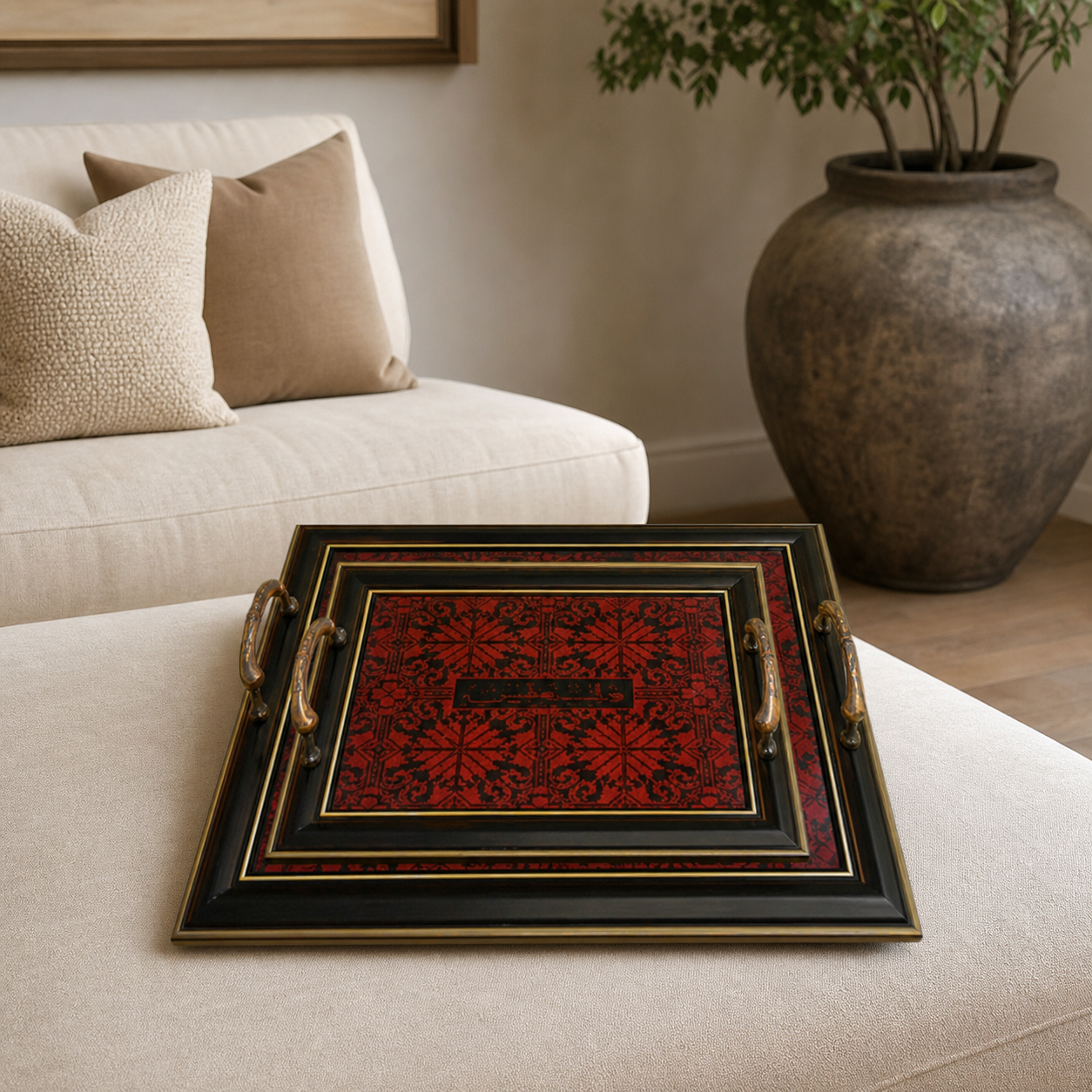 Black two-piece tray set with red patterned panel and bronze-tone handles, on a cream ottoman