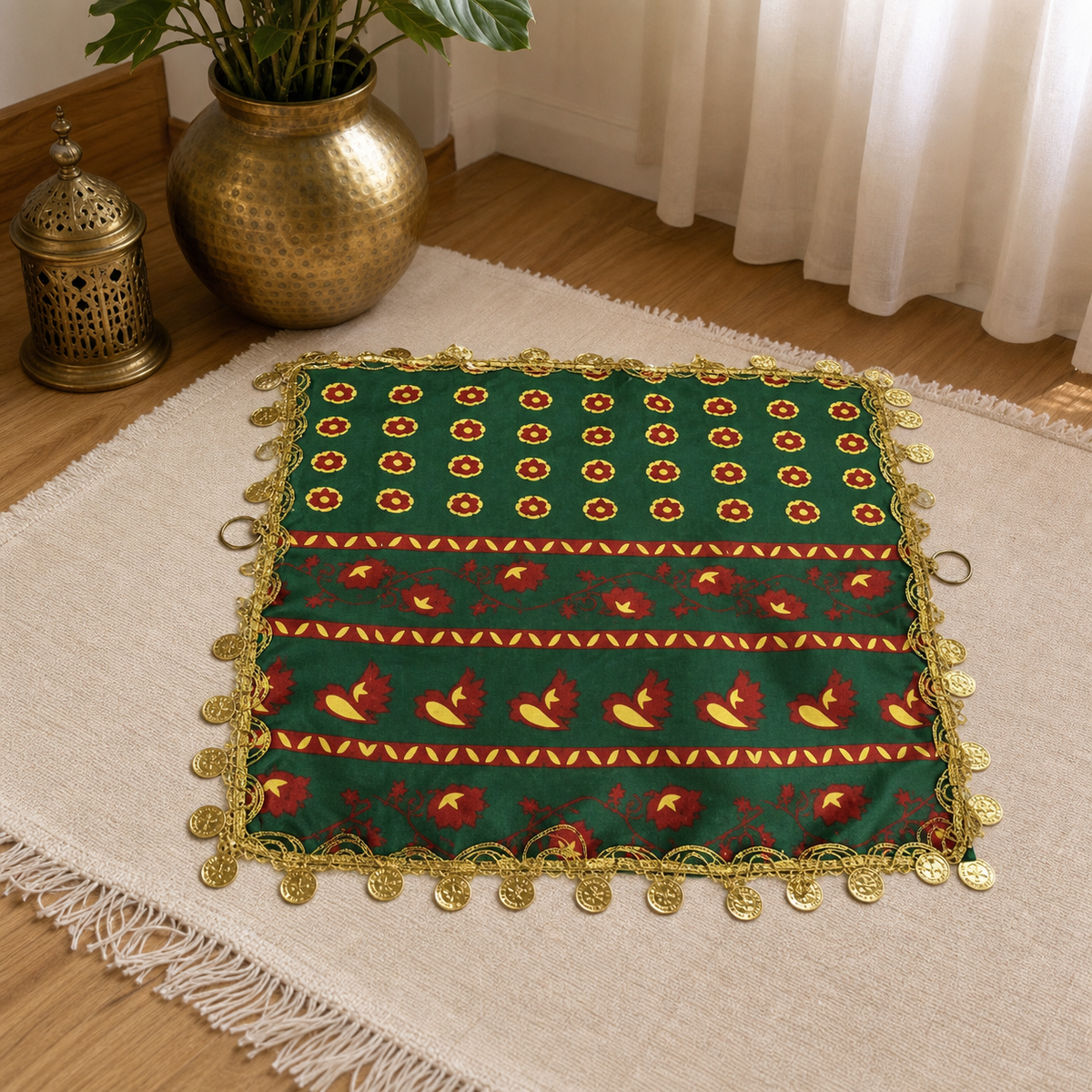 Green coin-trimmed dancing scarf on a woven rug, with a gold-tone metal ring at each side edge