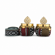 Two fabric-covered favor pots with gold-tone lids and palmette finials, beside a fabric-topped pot