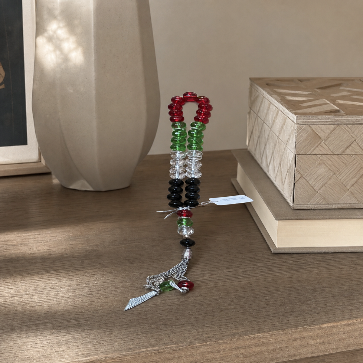 Banded tasbeeh with silver-tone tassel resting on a wooden table