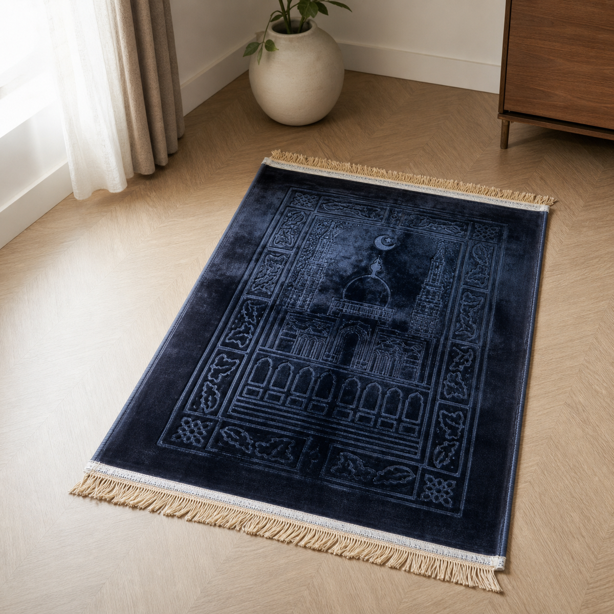 Navy velvet prayer mat with cream fringe laid on a herringbone wood floor