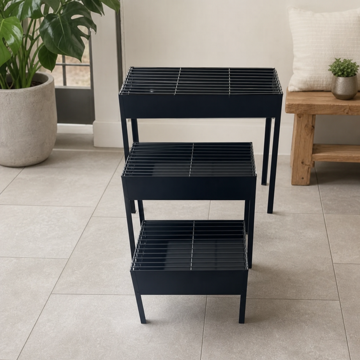 Three graduated black charcoal grills staged indoors on a tiled floor