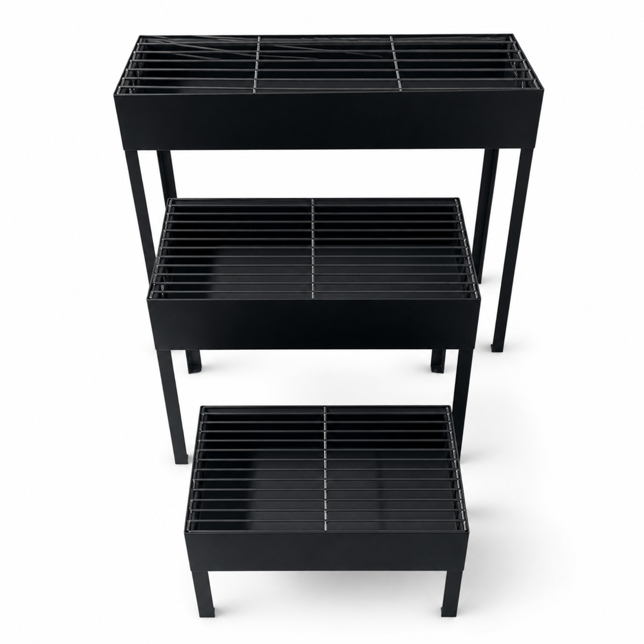 Three black rectangular charcoal grills of graduated size on straight legs
