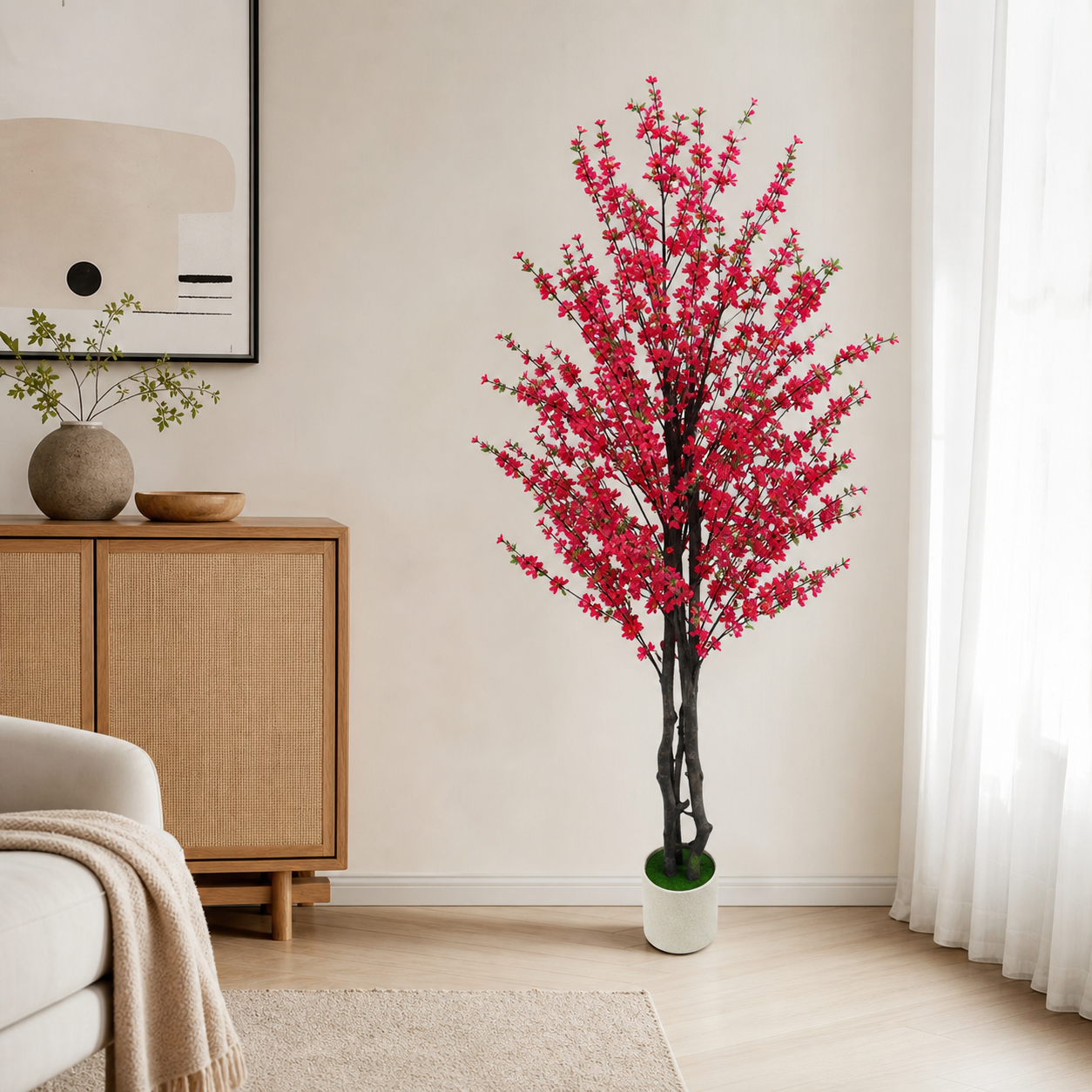Artificial red blossom tree in a white pot beside a rattan sideboard in a bright living room