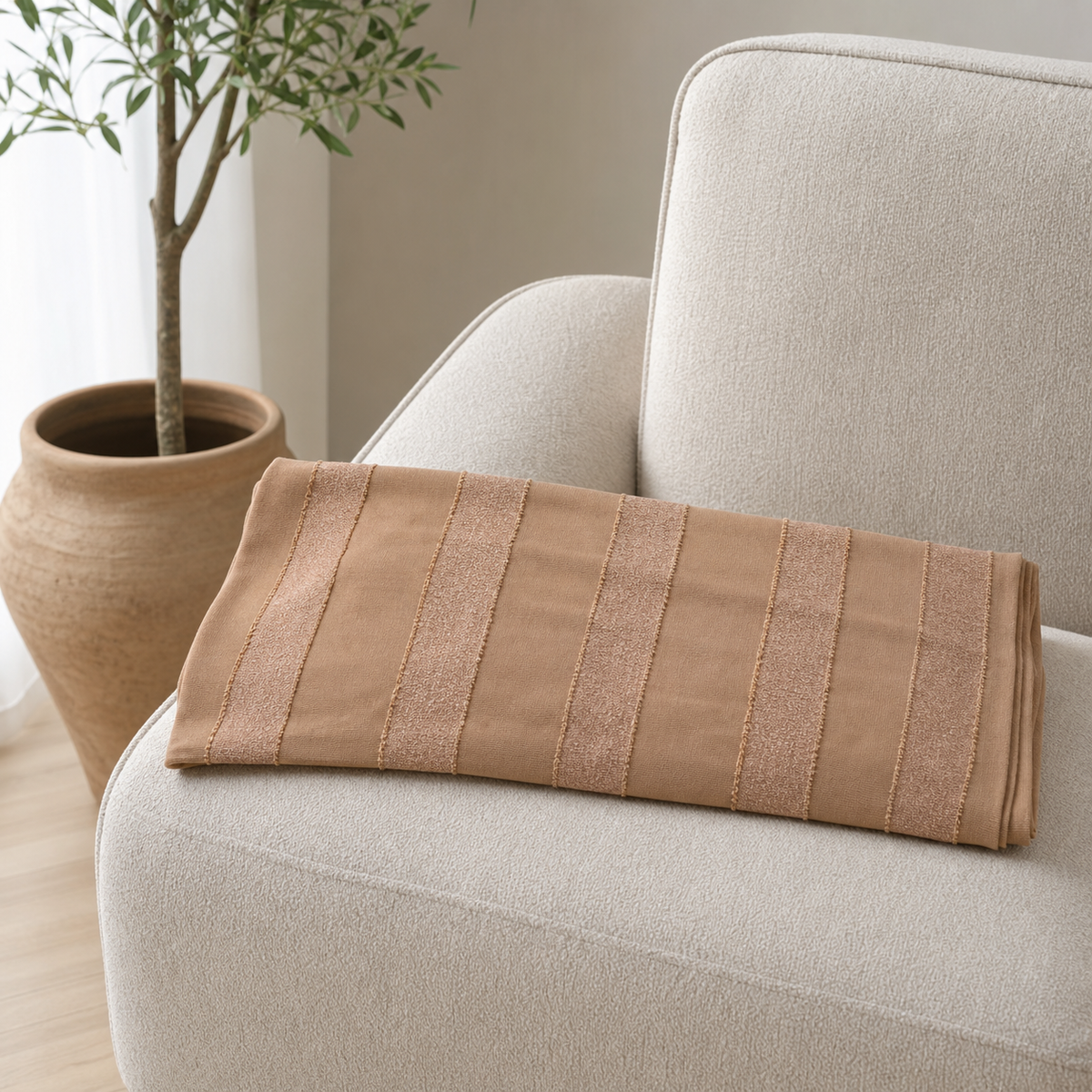 Camel-tan scarf with gold metallic stripes draped over the arm of a cream boucle armchair