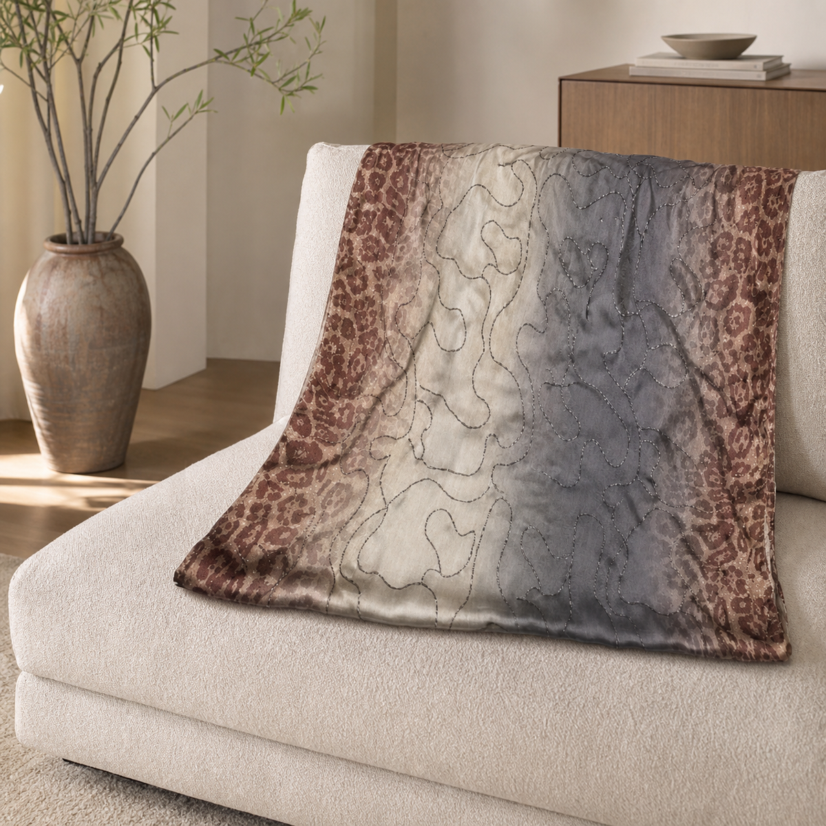 Leopard-border scarf with cream-to-grey glitter-swirl centre, spread over a cream sofa seat