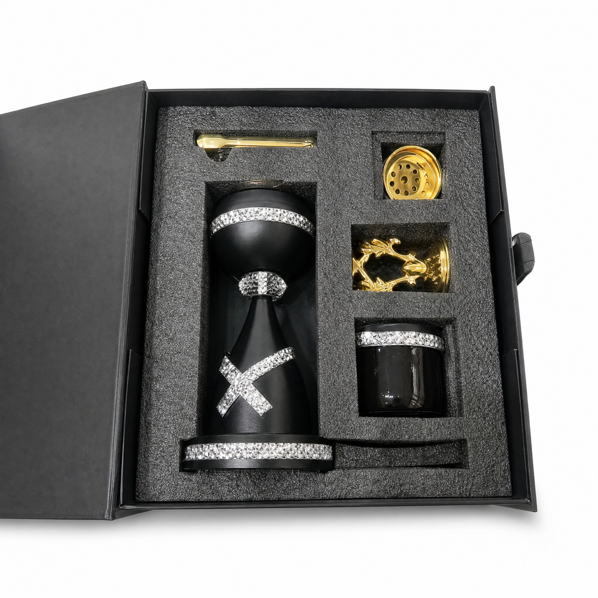 Open black gift box with a black burner and cup banded in clear stones, plus gold spoon and accessories