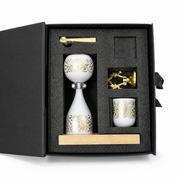 Open gift box with a white and gold burner, matching cup, gold spoon and gold openwork piece