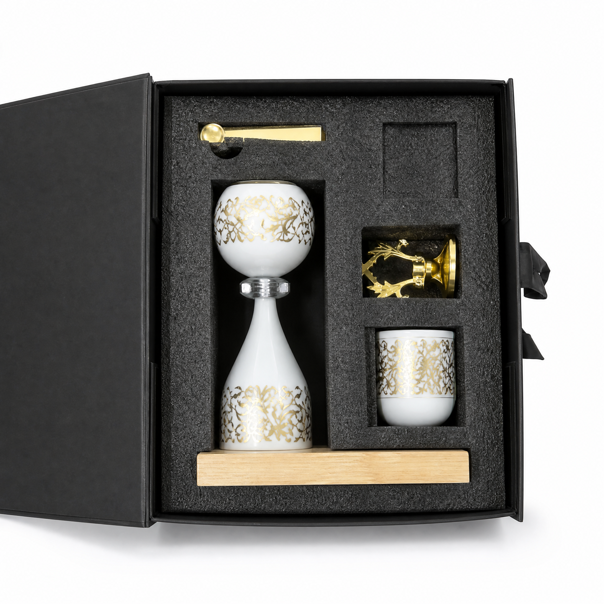 Open gift box with a white and gold burner, matching cup, gold spoon and gold openwork piece