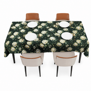 Dark green table cover with cream rose print, spread over a rectangular dining table set for four