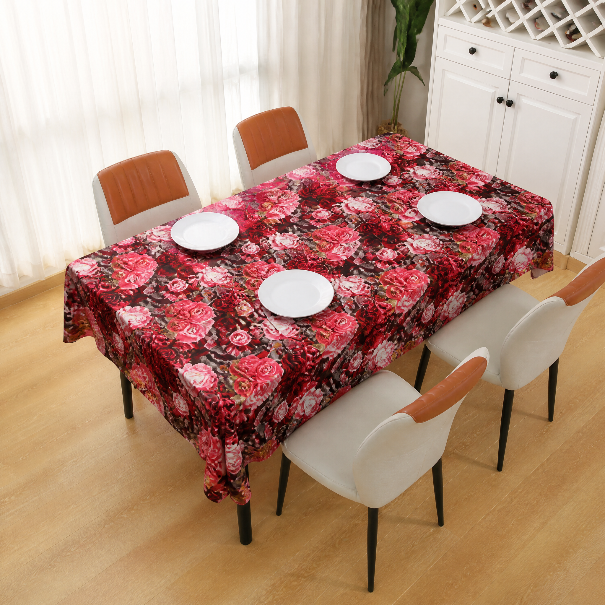 Pink and red rose-print table covering on a dining table in a room with a wooden floor and white cabinet