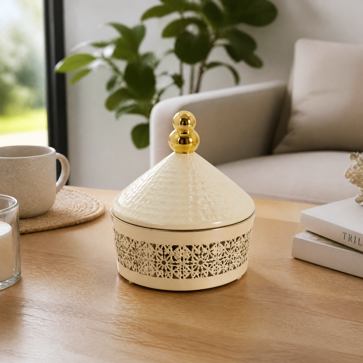 Cream candy box with a hammered cone lid and gold-tone ball finial, on a wooden table