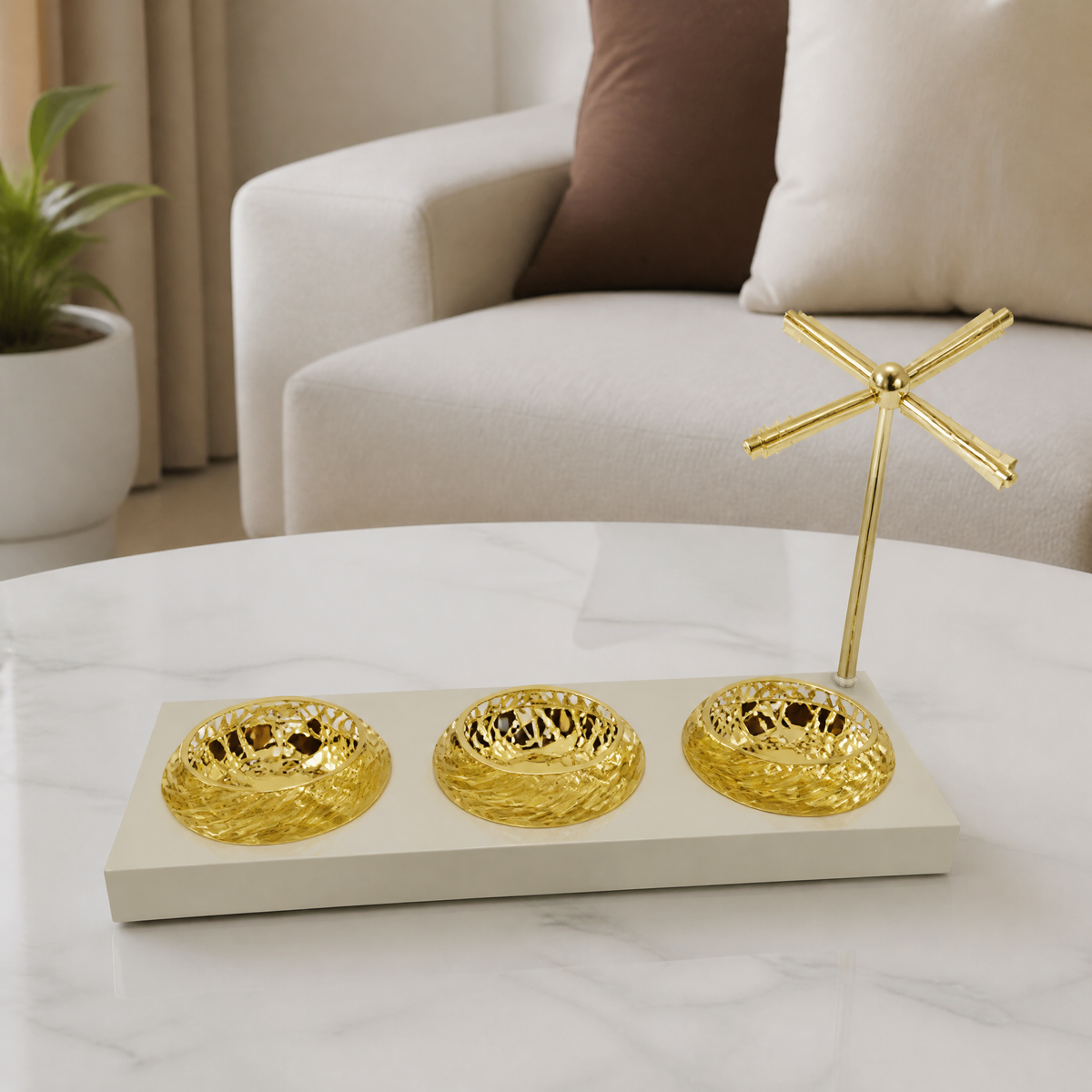 Three open gold dishes on a pale cream tray with a tall gold crossed-rod stand