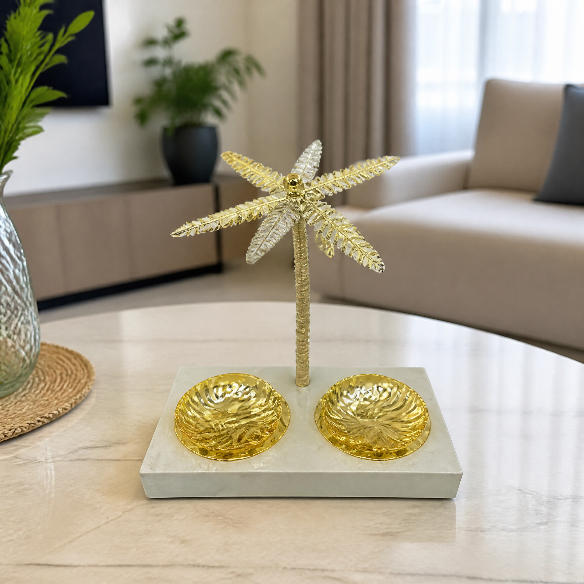 Gold palm tree stand with two round gold dishes on a pale tray, on a marble table