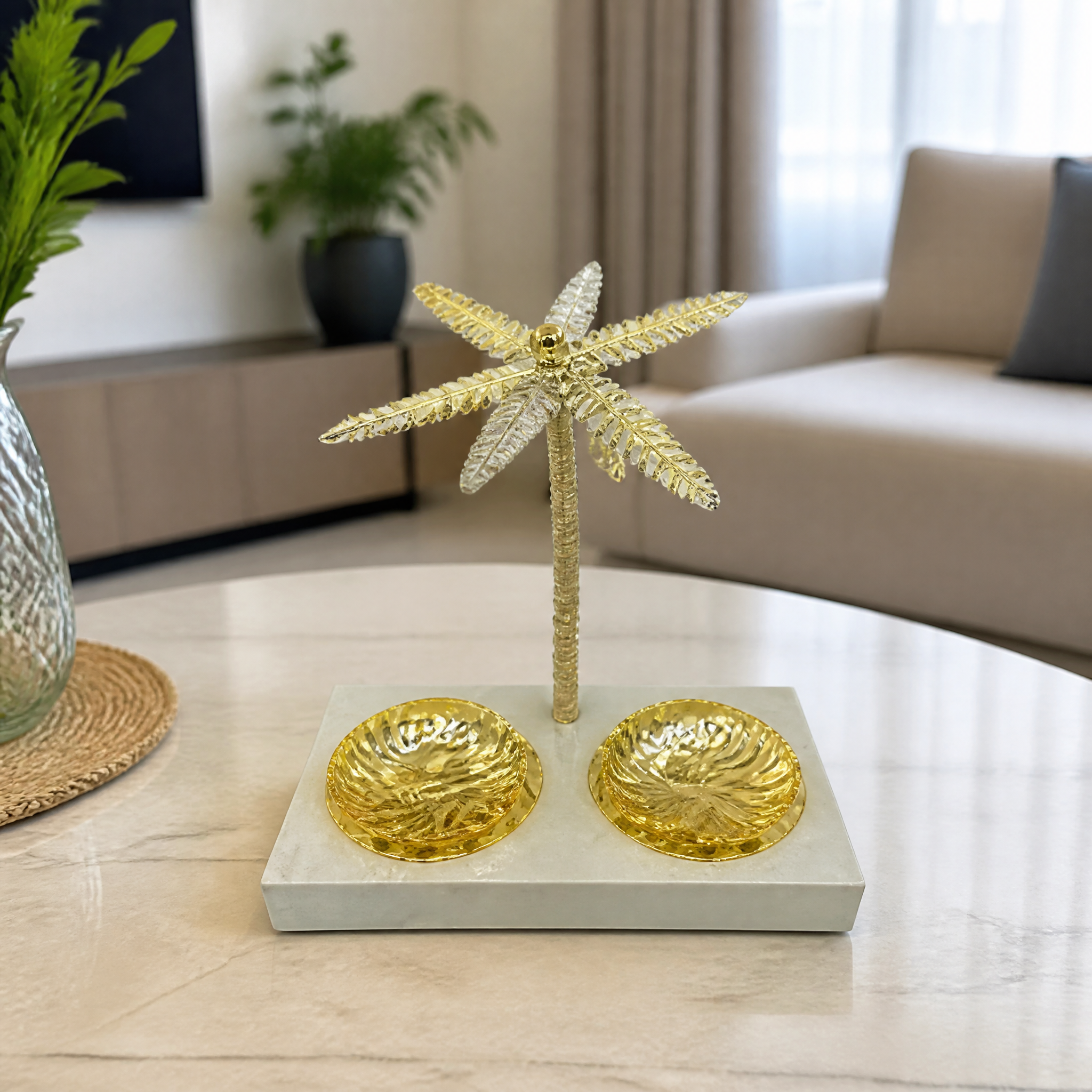 Gold palm tree stand with two round gold dishes on a pale tray, on a marble table