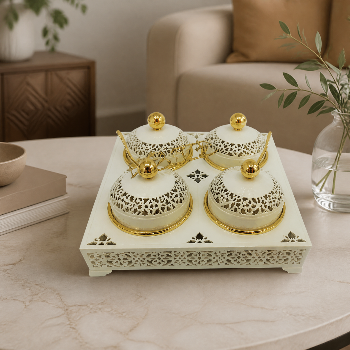 Ivory and gold four-jar candy set with gold spoons on a round marble table in a living room