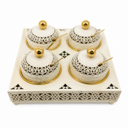 Four ivory and gold lidded jars with ball finials, two by two on a pierced ivory tray