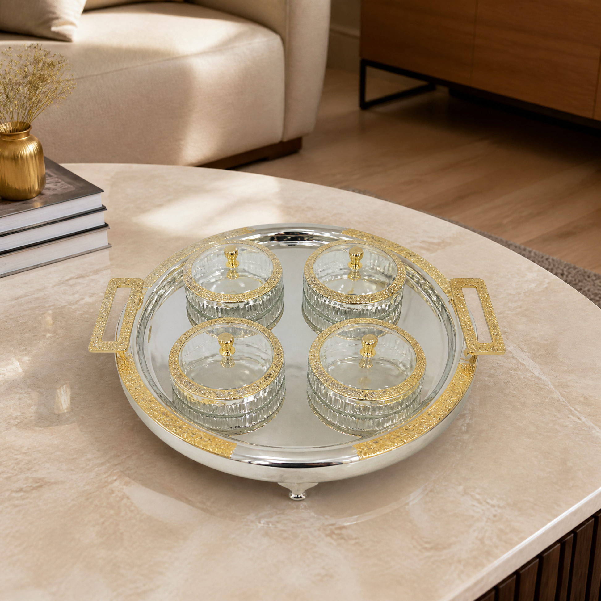 Round silver and gold tray of four lidded glass bowls on a marble coffee table