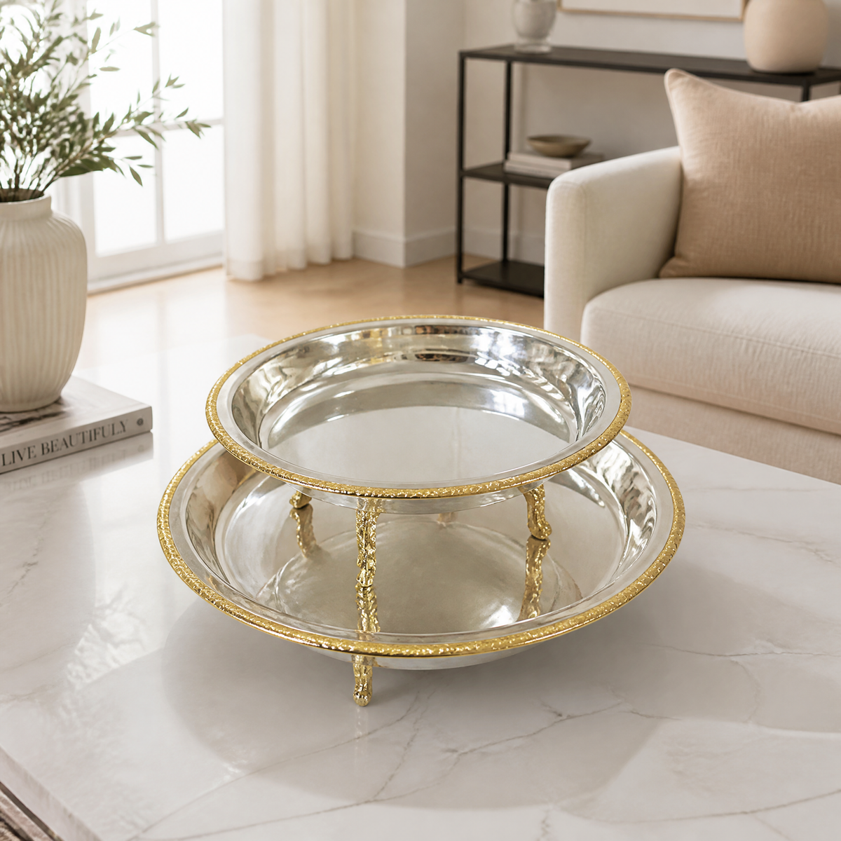 Footed round silver and gold serving bowl with a mirror finish and braided gold rim