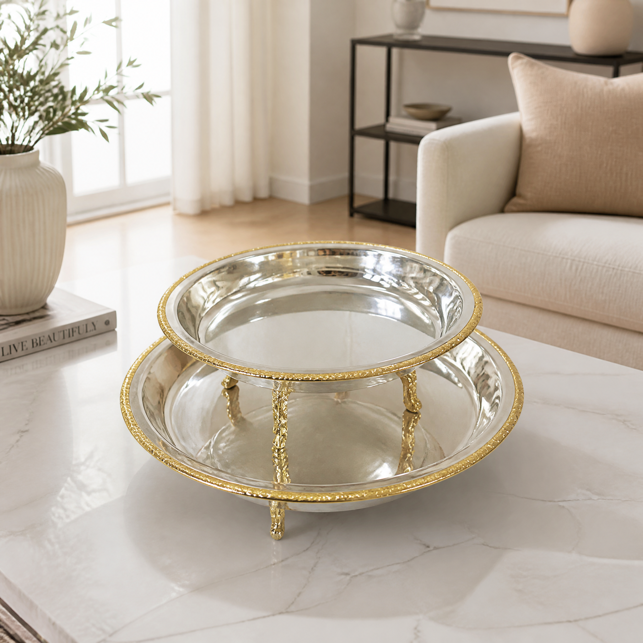 Footed round silver and gold serving bowl with a mirror finish and braided gold rim