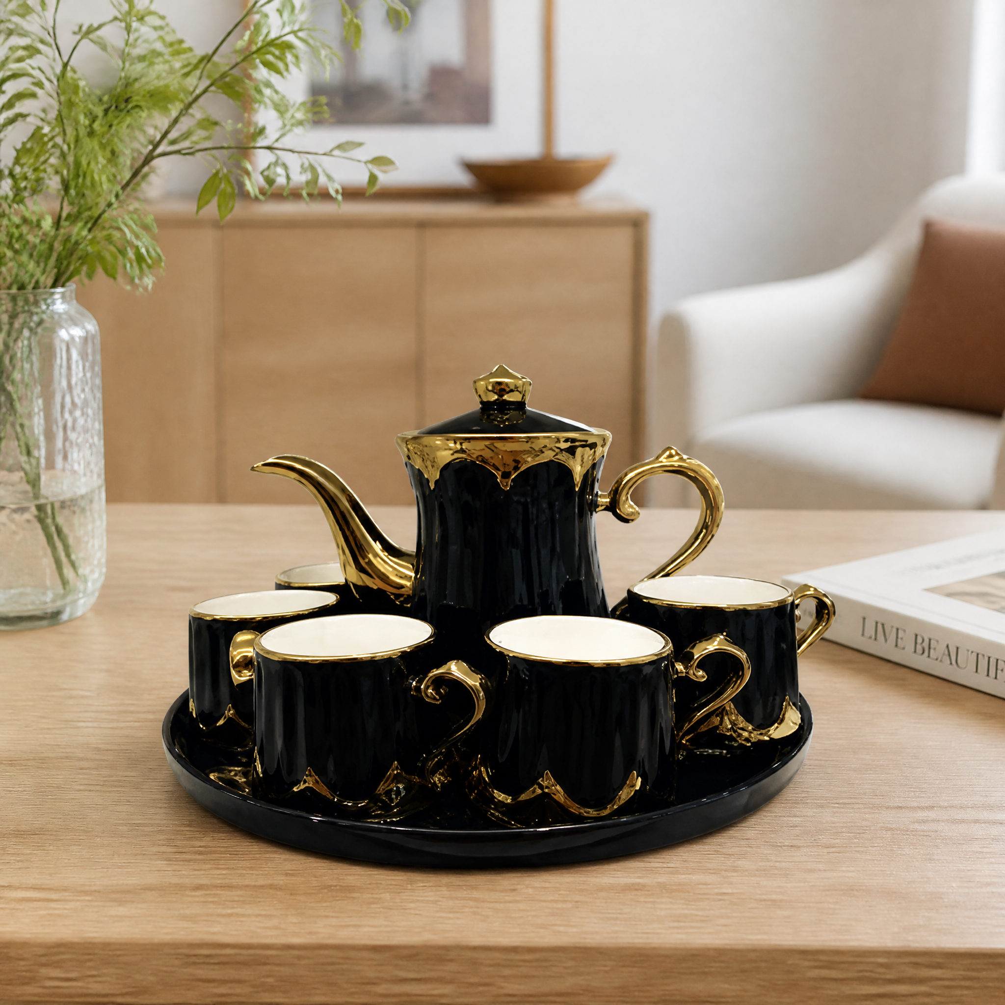 Black and gold tea service with a lidded teapot cups and an oval tray
